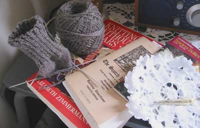 Partially knit sock, crochet doilies, knitting and crochet books