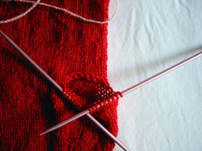 Pull out the yarn used to hold the stitches